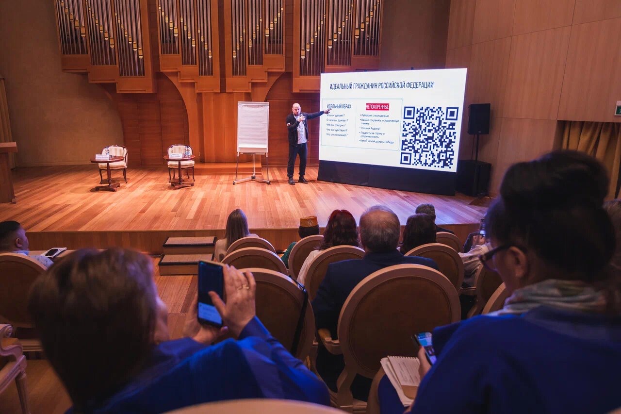 Органный зал в Ханты-Мансийске: ведущий на сцене, на экране опрос с QR-кодом