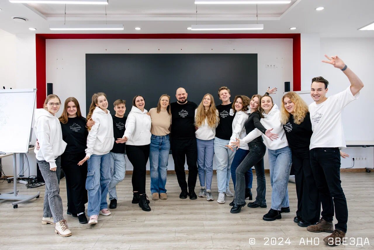 Команда трекеров АНО «ЗВЕЗДА»: 14 человек стоят в ряд в зале